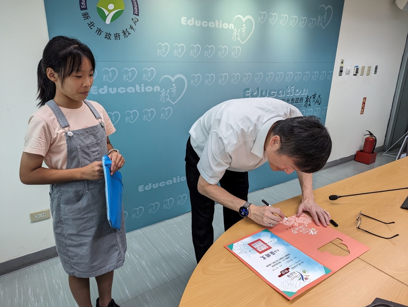 廣福國小學生黃子綺參加「阿文局長的午茶時間」，當面請教育局長張明文在局長獎獎狀上簽名。